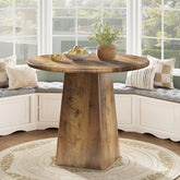 Wooden dining table with a round top and a single pedestal base in a room with large windows. 3